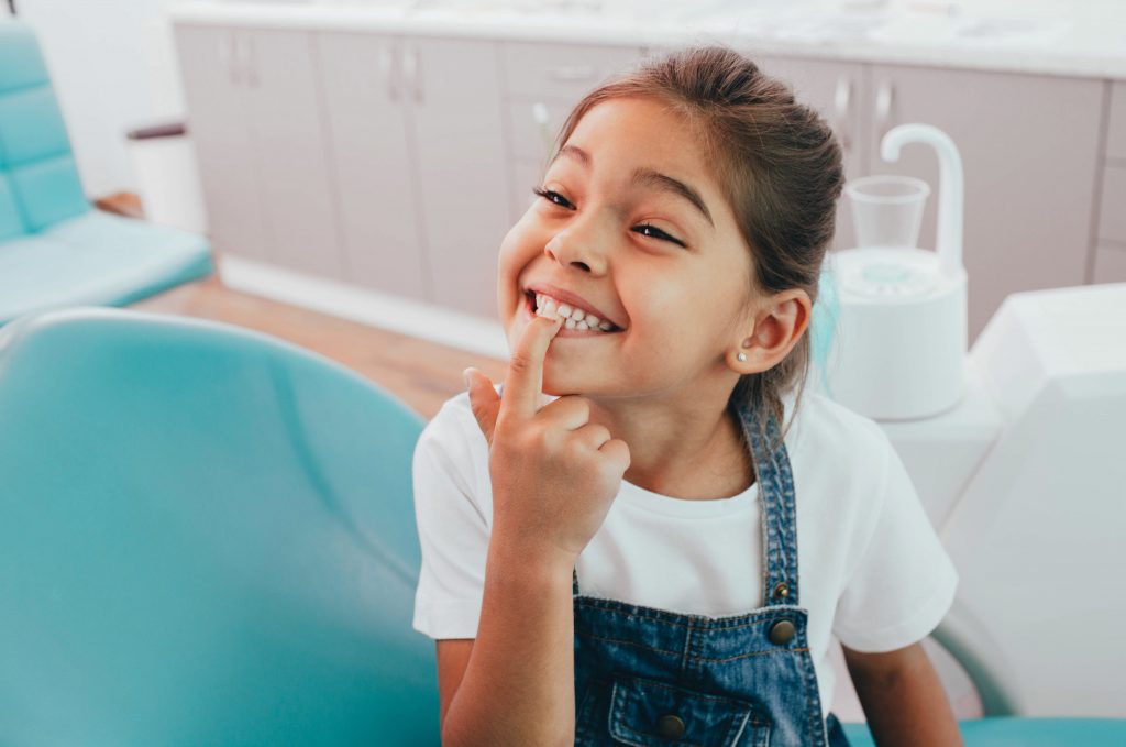 Mädchen zeigt ihre Zähne beim Kinderzahnarzt